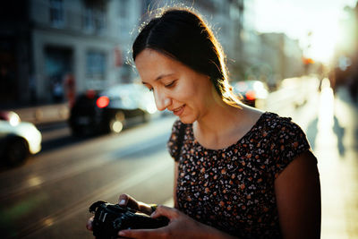 Mid adult woman photographing while standing on road in city