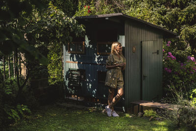 Thoughtful mature woman leaning on store house in garden