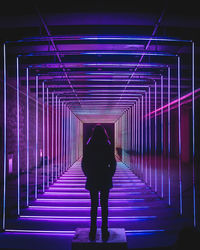 Rear view of woman standing on illuminated walkway