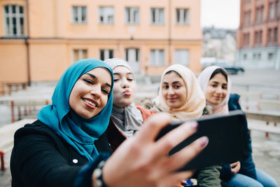 Portrait of smiling young woman using mobile phone in city