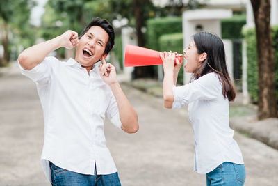 Woman shouting through megaphone while man covering ears