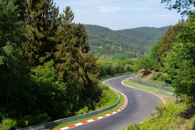 Road amidst trees and mountains against sky