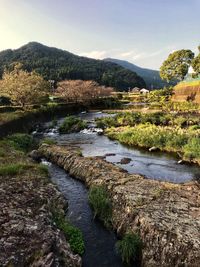 Scenic view of river by mountains against sky