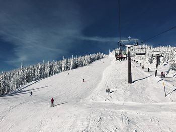Ski lift by snow covered mountain against sky