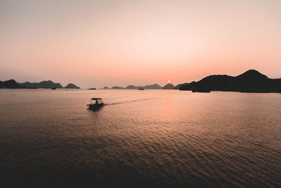 Silhouette boat sailing in sea at sunset