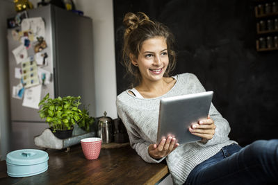 Smiling woman sitting at table holding tablet