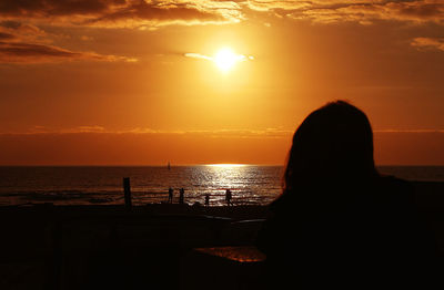 Silhouette man on beach against sky during sunset