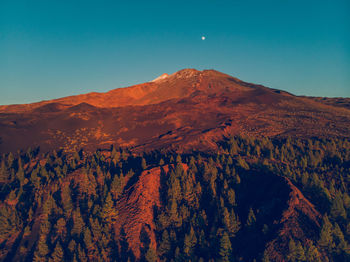 Scenic view of land and mountains against clear blue sky