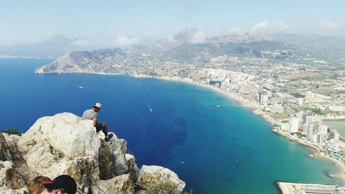 High angle view of man sitting on calpe rock by sea