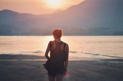 Full length of woman standing on beach during sunset