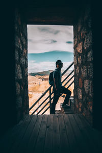 Man standing on railing against sky