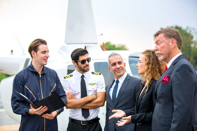 Business people discussing while standing against air vehicle