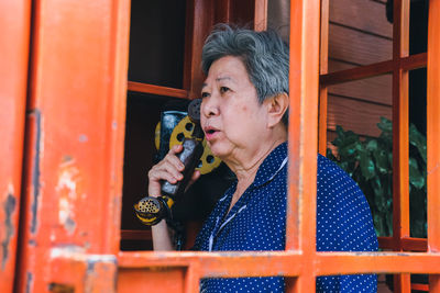 Senior woman talking on phone in telephone booth