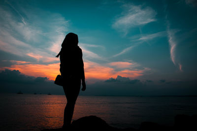 Silhouette man standing by sea against sky during sunset