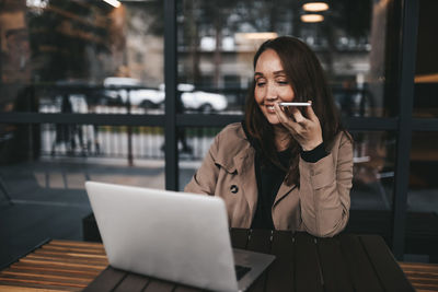 Young woman using mobile phone at table