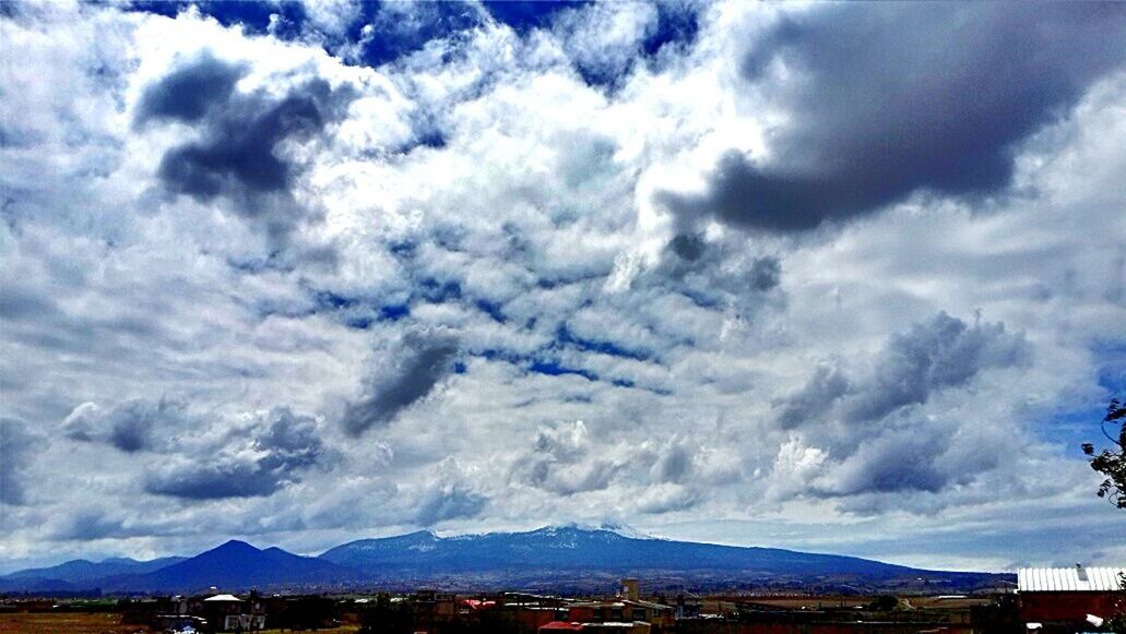 sky, building exterior, cloud - sky, architecture, built structure, mountain, cloudy, cloud, cityscape, mountain range, city, residential district, town, house, residential building, scenics, blue, residential structure, beauty in nature, nature