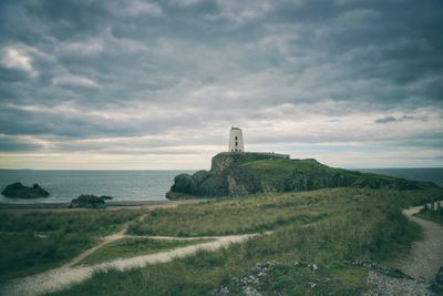 Lighthouse by sea against sky