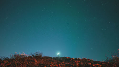 Low angle view of illuminated lighting equipment against star field