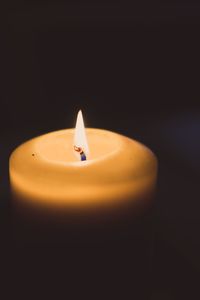 Close-up of lit candle against black background