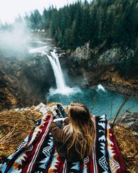 High angle view of woman relaxing on mountain by waterfall