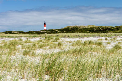 Lighthouse on field against sky