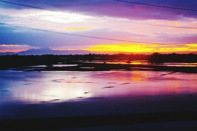 Scenic view of lake against dramatic sky during sunset