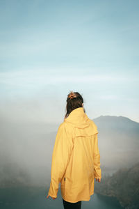 Rear view of man standing on mountain against sky