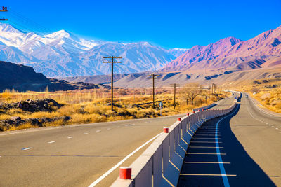 Road by snowcapped mountains against sky
