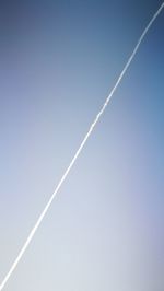 Low angle view of vapor trail against clear blue sky