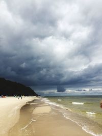 Scenic view of beach against cloudy sky