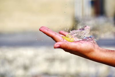 Close-up of hand holding water burst of balloon against blurred background