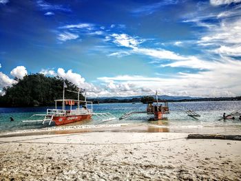 Boat moored on beach against sky