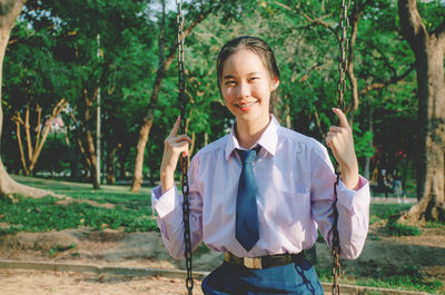 Portrait of smiling young woman standing against trees