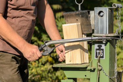 Midsection of man cutting wood with machinery