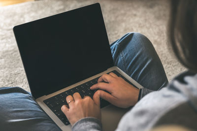 Midsection of woman using laptop at home