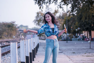 Portrait of smiling young woman standing against trees