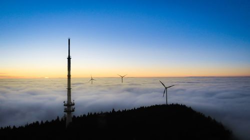 Silhouette of wind turbine against sky during sunset