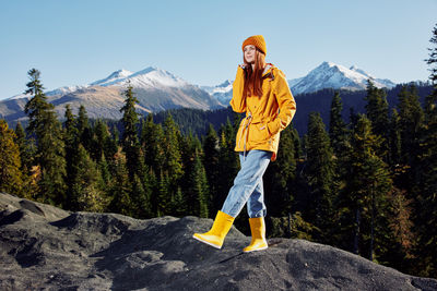 Full length of woman standing on rock against mountain