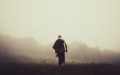 Rear view of man walking on field against sky