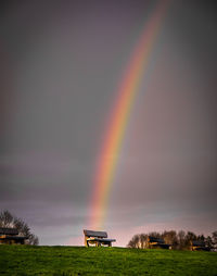 Rainbow over field against cloudy sky