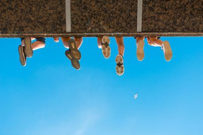 Low section of shoes hanging against blue sky