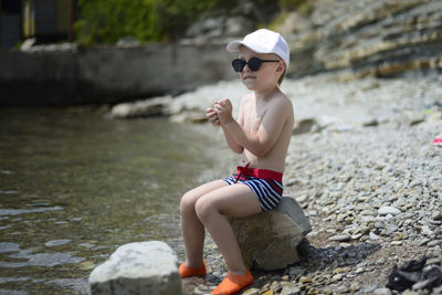 Rear view of boy sitting on shore