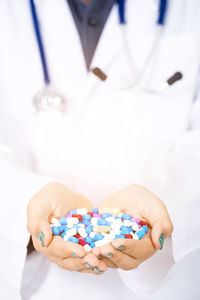 Midsection of female doctor holding pills