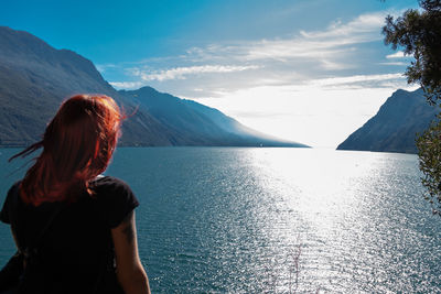 Rear view of woman looking at mountains against sky