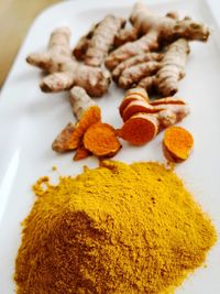 Curcuma turmeric powder and roots on white plate background