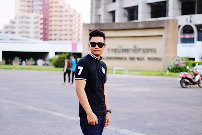 Portrait of young man wearing sunglasses while standing in city