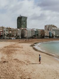 Man on beach against buildings in city