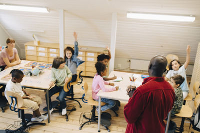 High angle view of male teacher looking at students in classroom