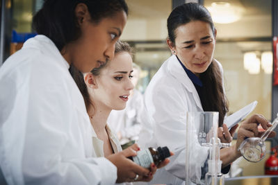 Mature teacher with young female students learning chemistry at laboratory