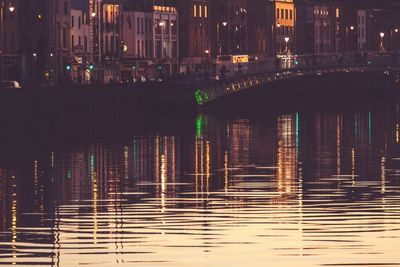 Illuminated bridge over river in city at night